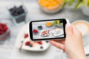 Woman taking a photo of breakfast with smartphone.